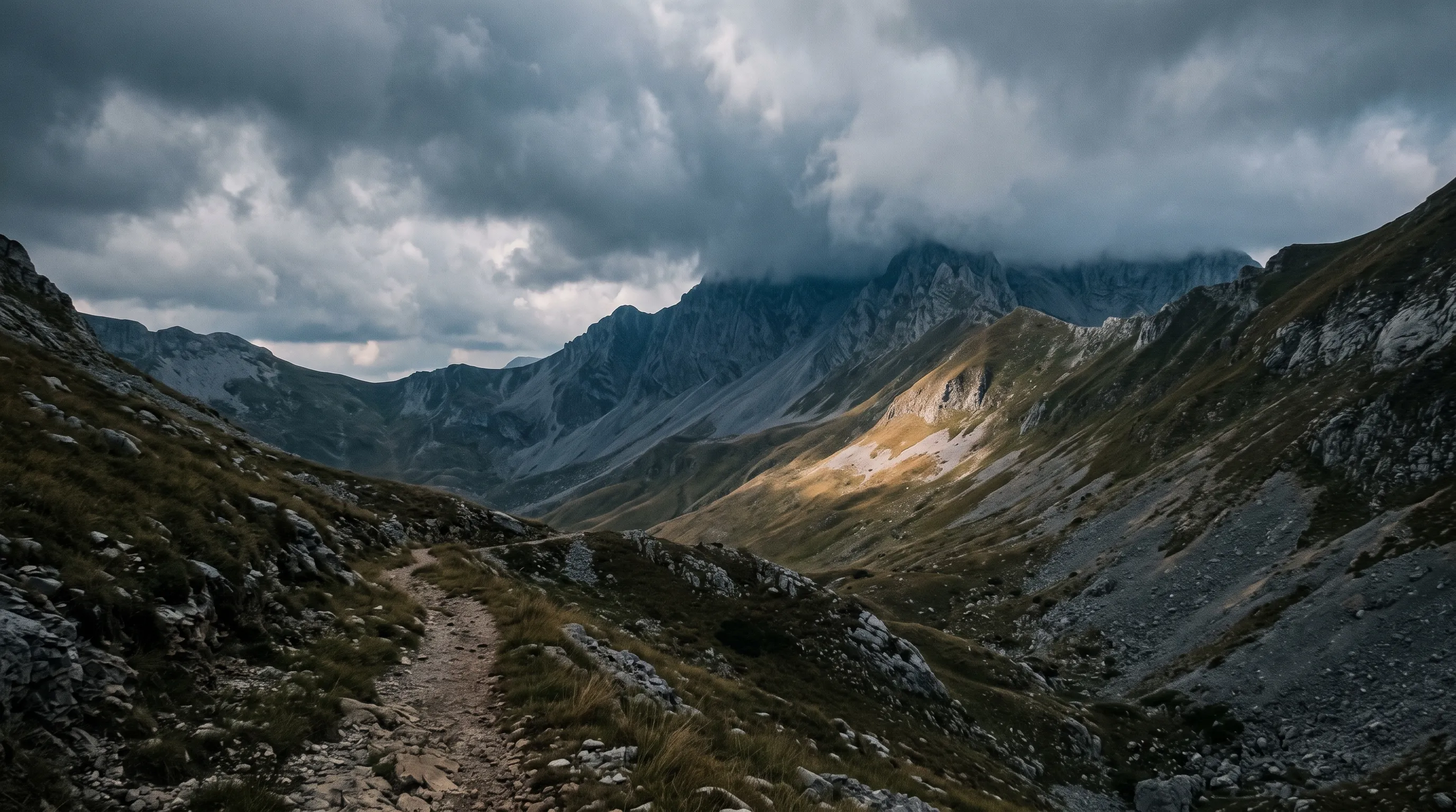 Horská dolina s chodníkom a mrakmi nad hrebeňom